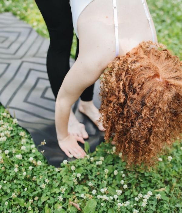 Woman stretching gracefully outdoors in a green park setting.